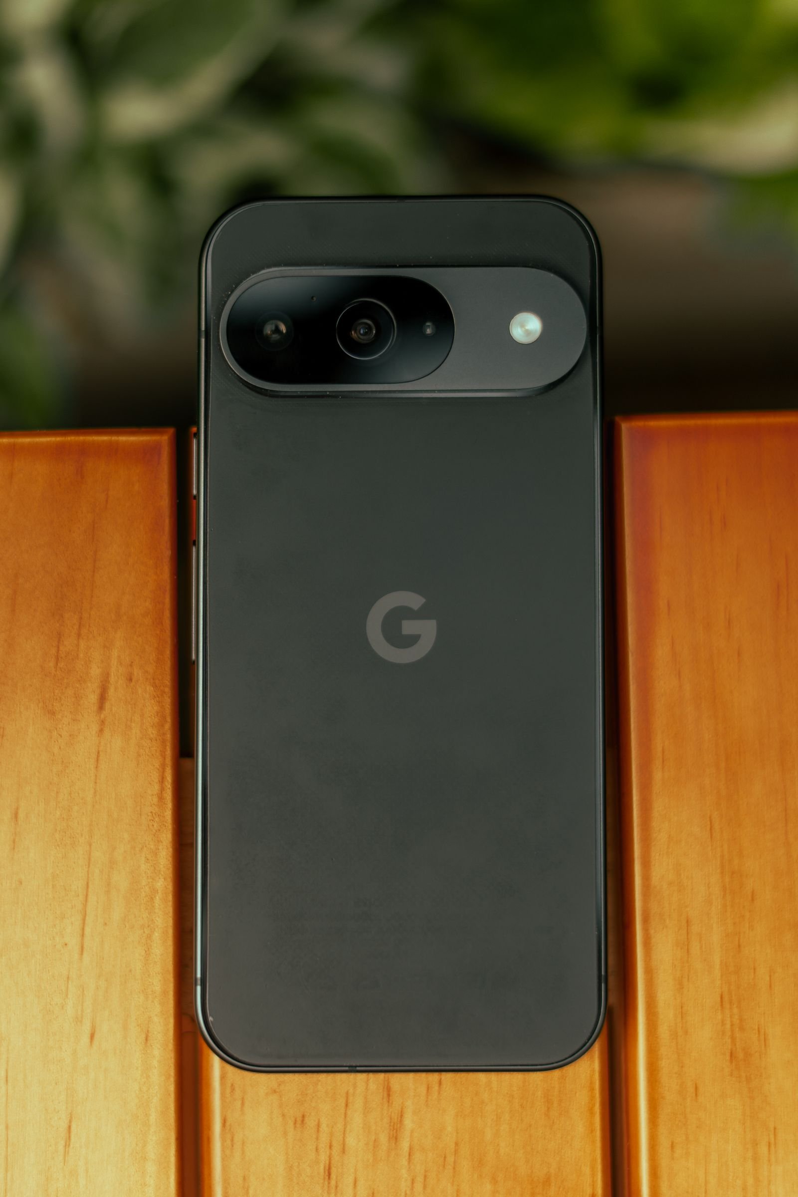 Close-up of a black smartphone on a wooden table, representing the premium design expected on Apple's next flagship phone