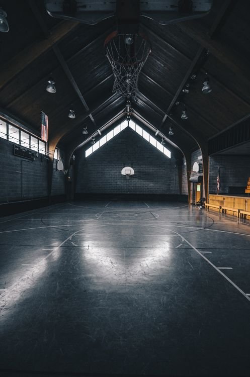 A dimly lit, empty basketball court between games