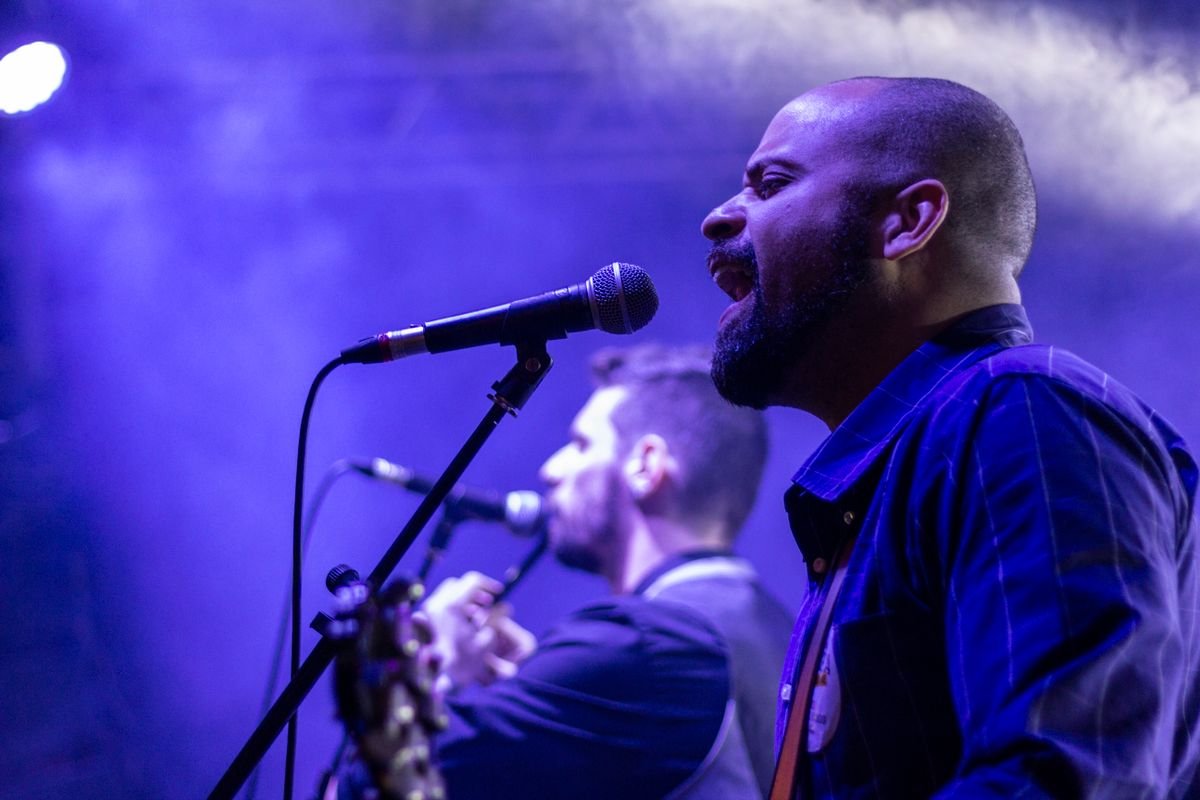 Musicians performing live on stage under warm concert lighting.