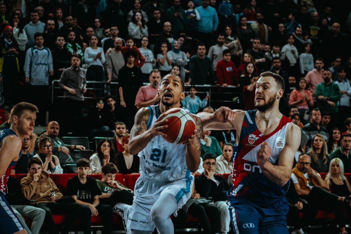 Basketball players compete on the court in front of a packed arena crowd during an NBA game