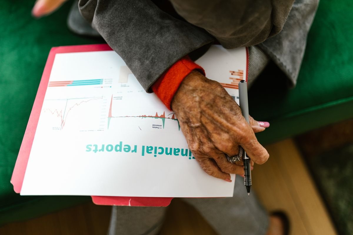An older woman reviewing a financial report with a pen