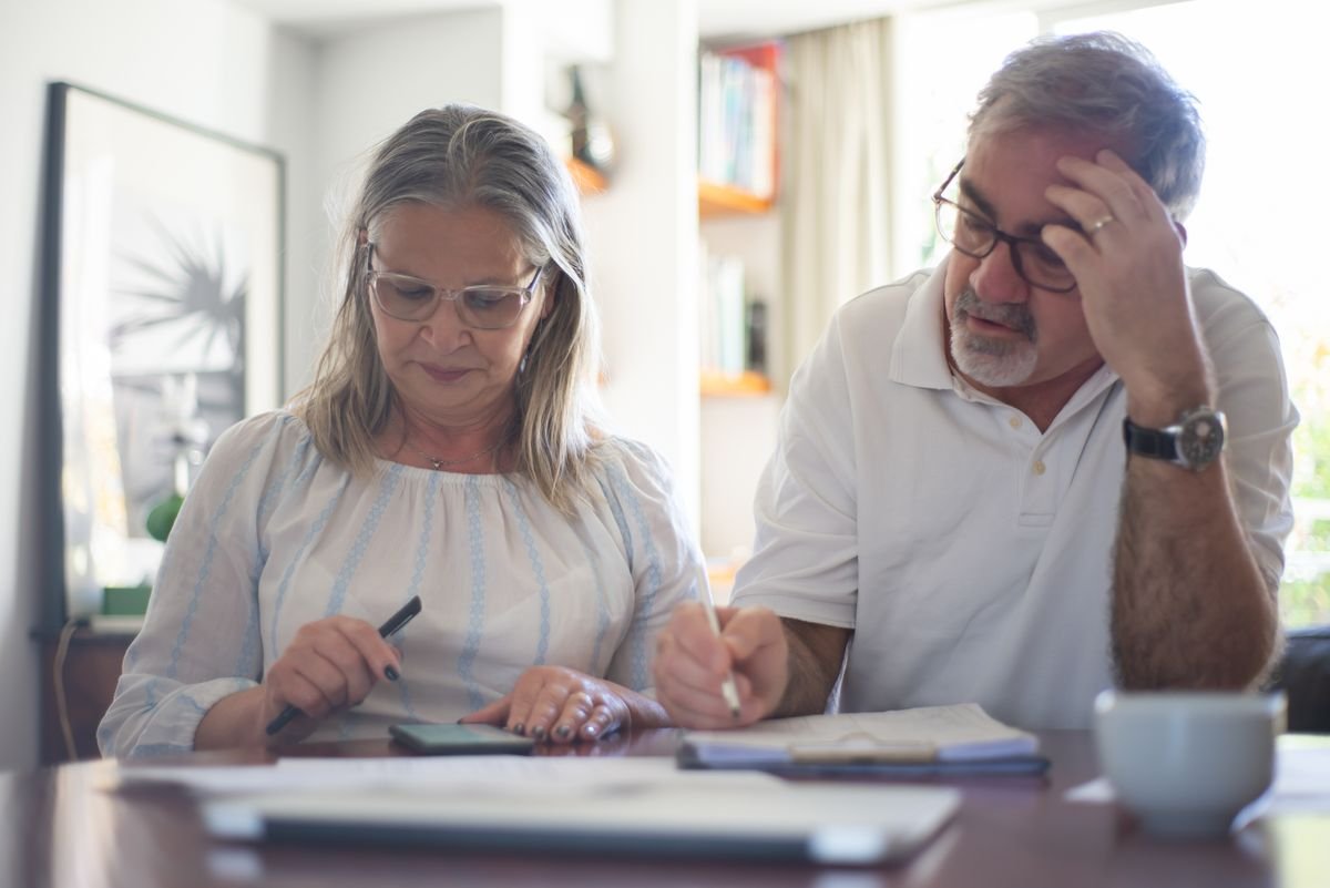 A senior couple reviewing expenses and documents at a desk